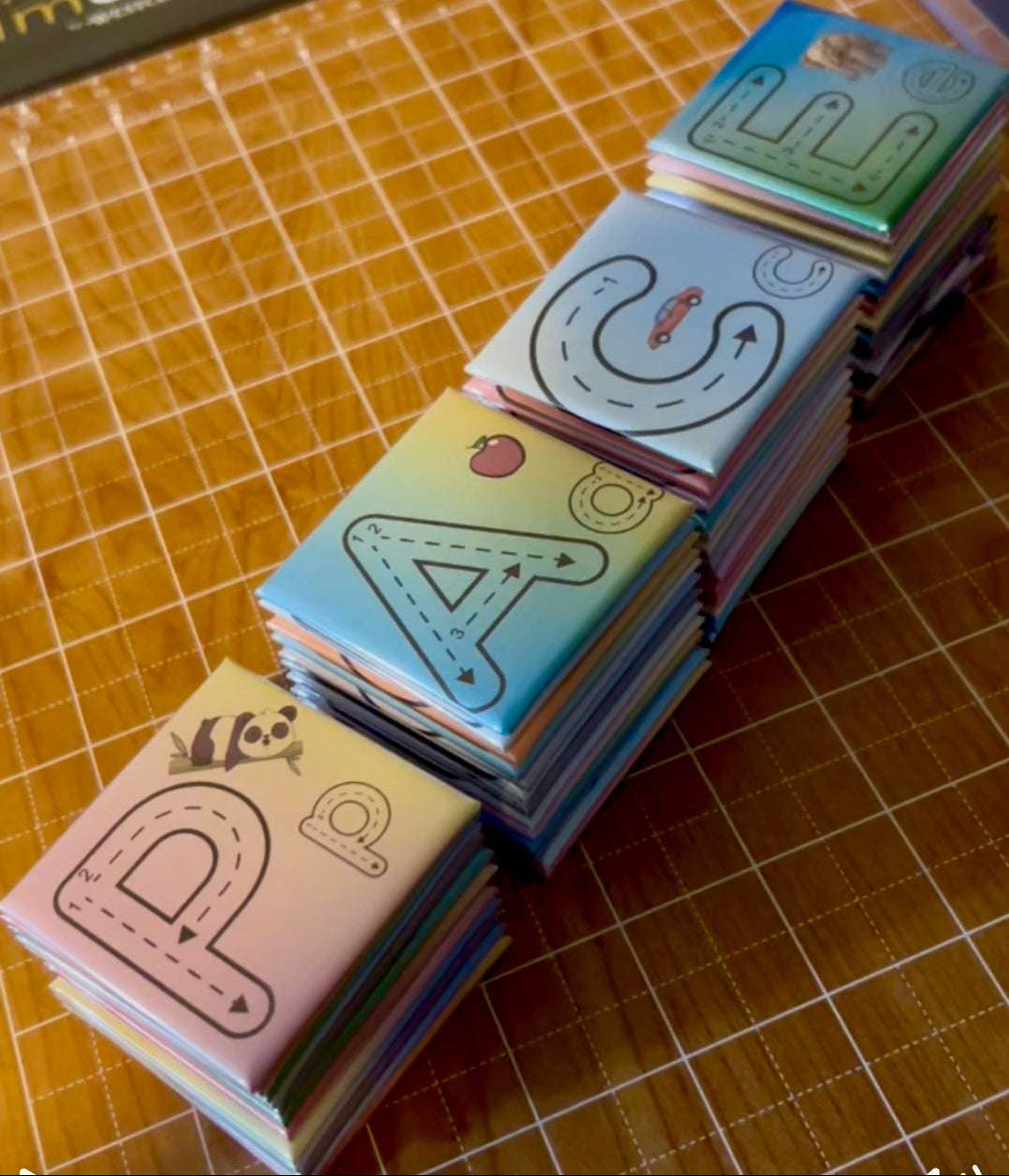 Stack of 2x2 ABC magnets with different letters and colors on a grid-patterned surface