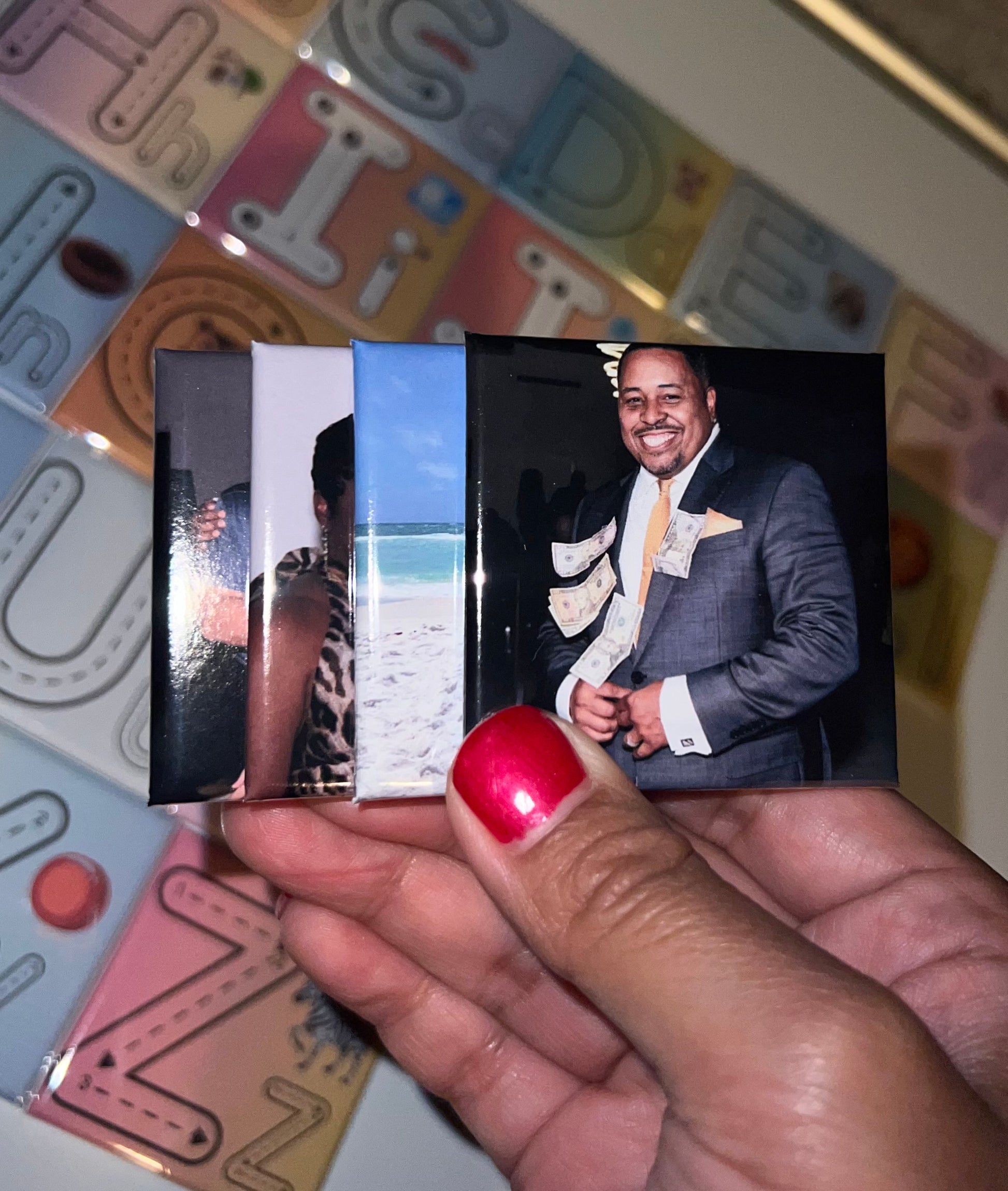 Hand holding 2x2 photo magnets with a man in a suit on a colorful background