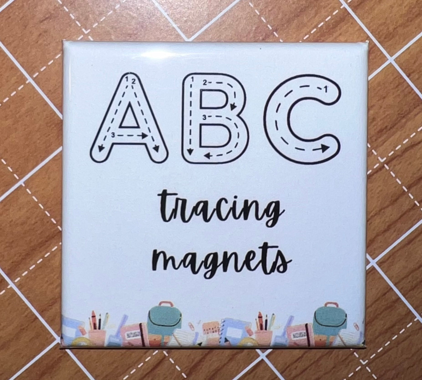 An image of a photo magnet with text "ABC tracing magnets" on a wooden surface