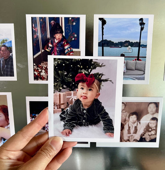 Collection of family photos displayed on a wall with a hand holding a photo of a child.