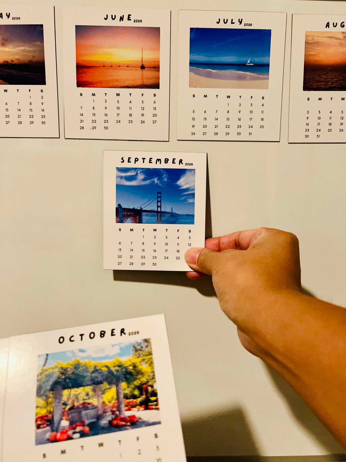 Hand holding a September calendar page with a view of the Golden Gate Bridge.
