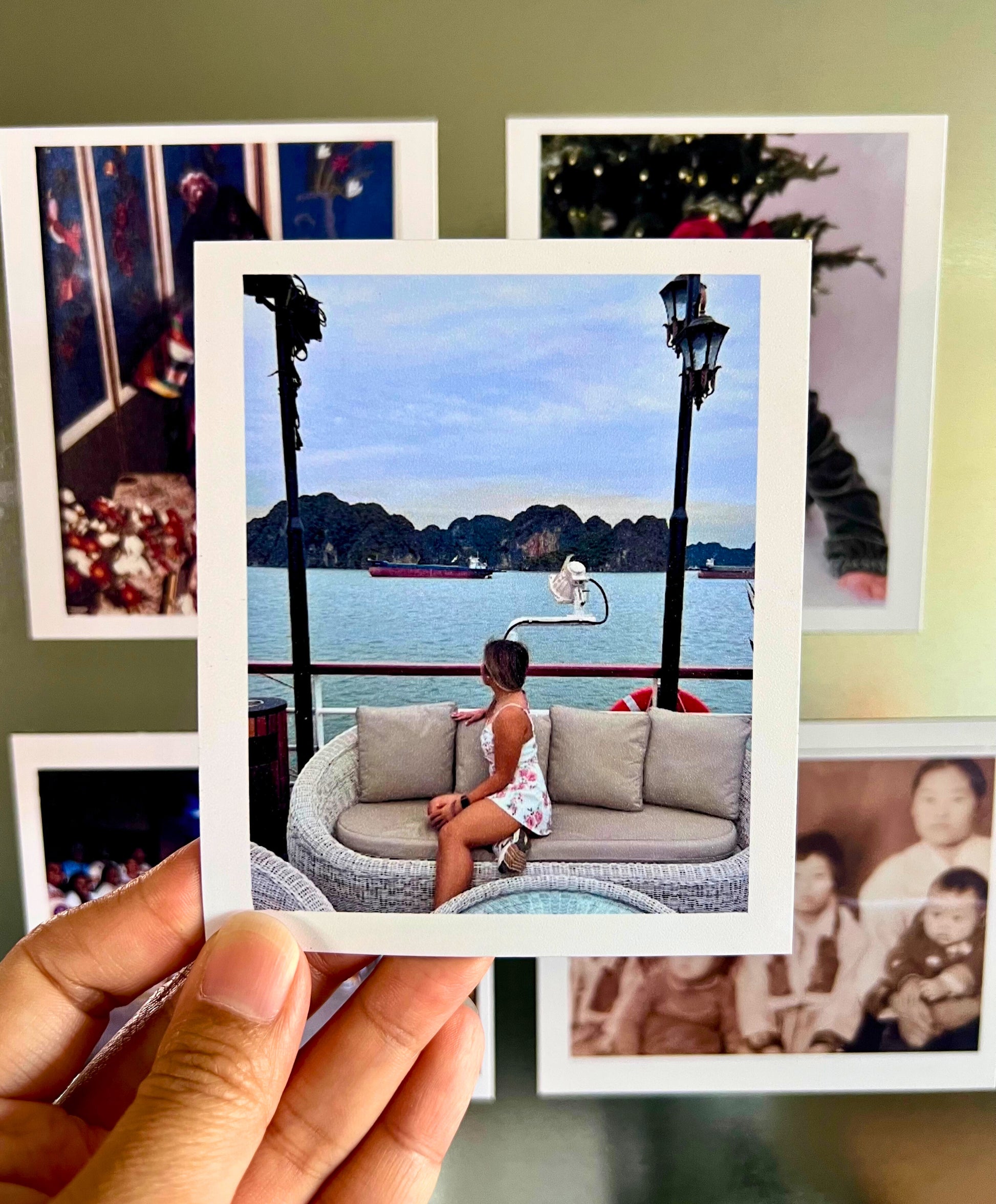 Person holding a flexible photo magnet of a woman sitting on a boat with a scenic view.