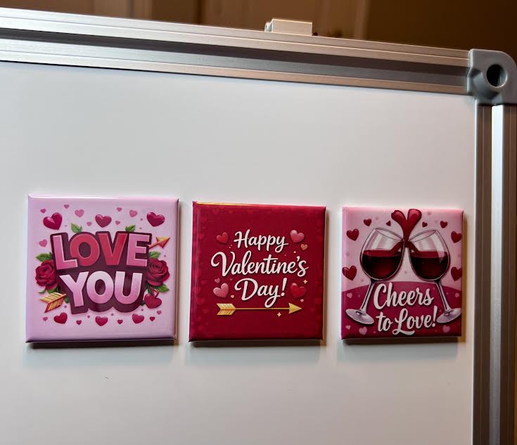 Three Valentine's Day-themed magnets on a whiteboard.