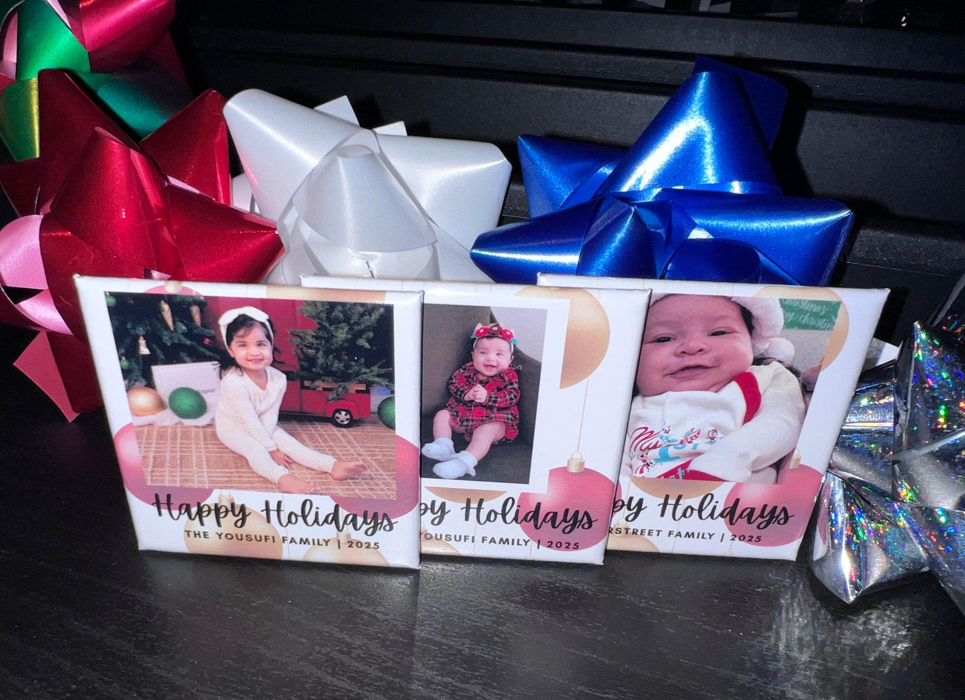 Three holiday photo magnets with children's photos and 'Happy Holidays' text, surrounded by colorful bows.